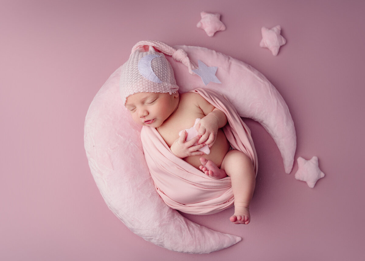 Newborn baby girl wrapped in pink wrap wearing pink hat during newborn photoshoot in Mount Juliet tennessee photography studio