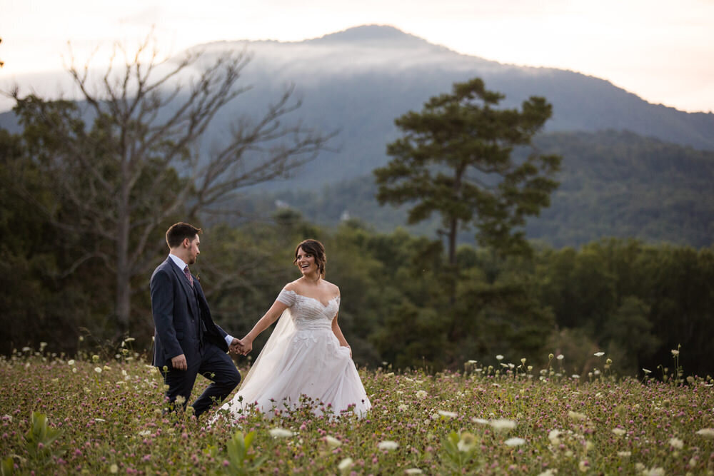 couple walks through a field of wildflowers in the mountains