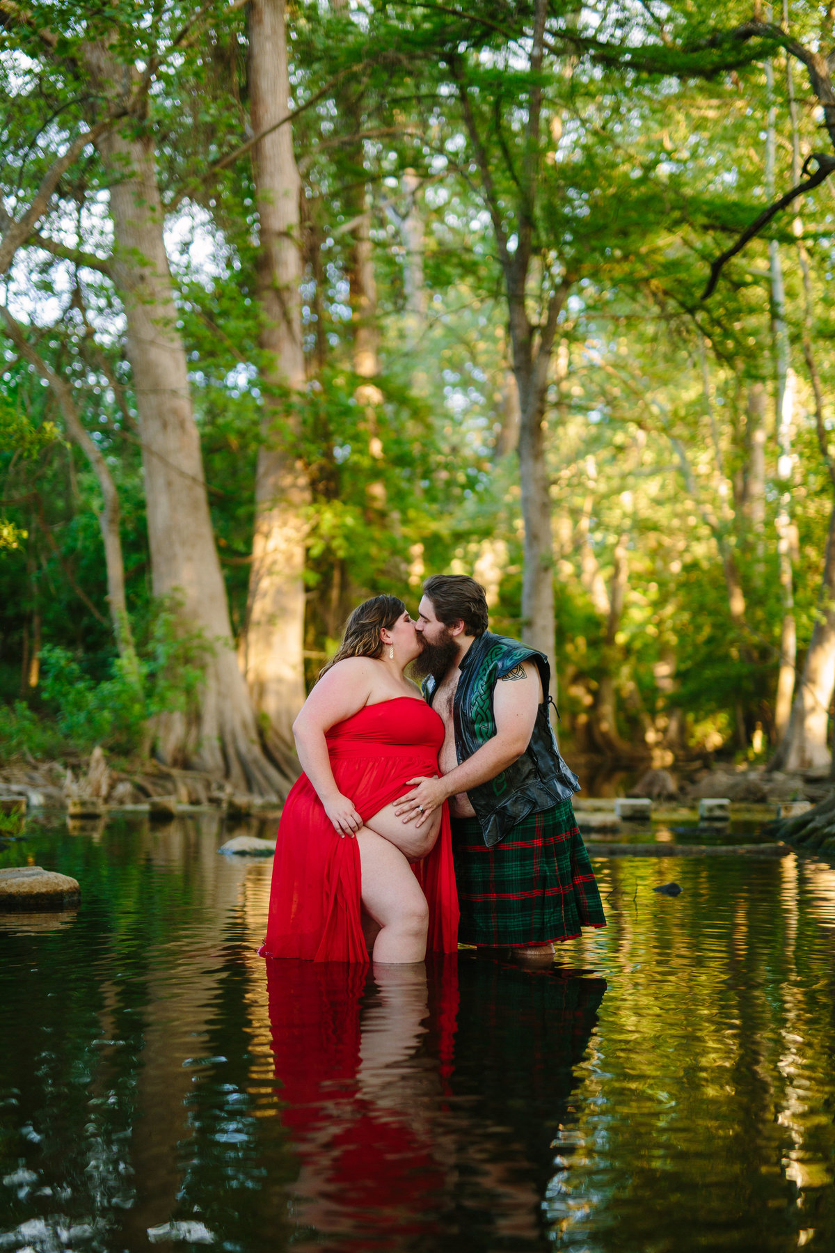 Pregnant couple standing in river holding each other for their maternity session in San Antonio.