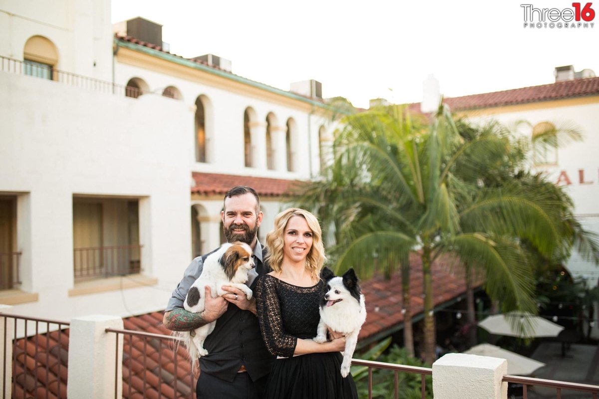 Engaged couple pose on the second floor of the Villa Del Sol with their small dogs