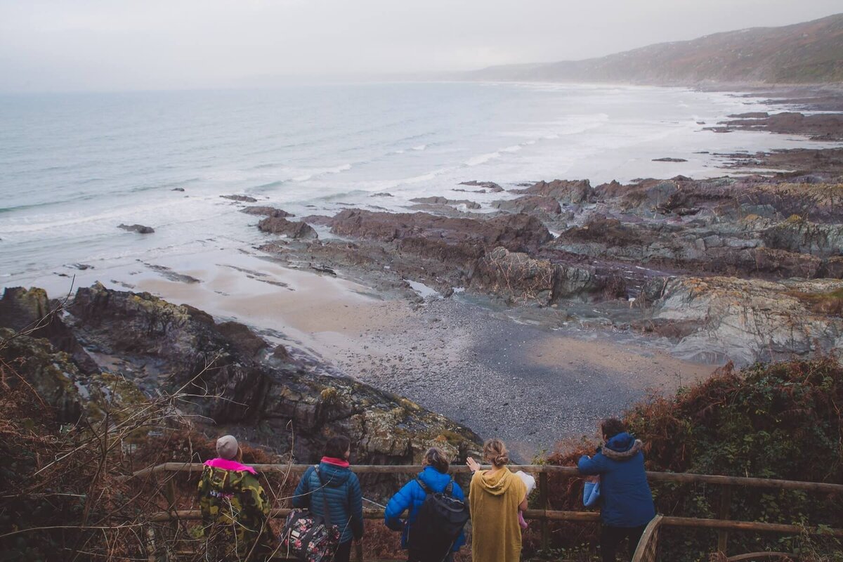 A group of people standing on a bridge looking down at the beach