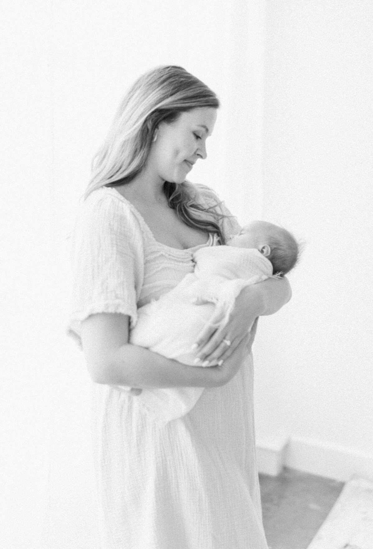 Black and white portrait of a woman holding a swaddled baby in her arms