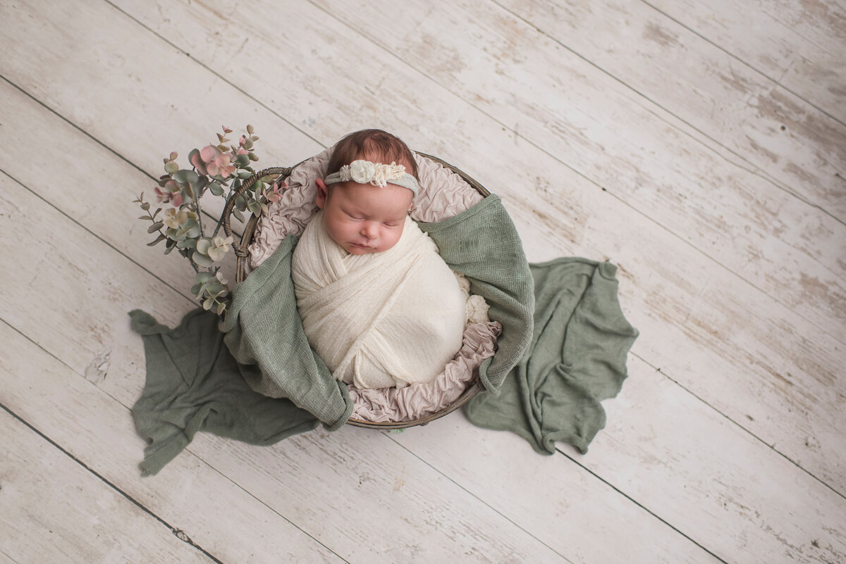 infant girl posed with green blanket and white background in studio