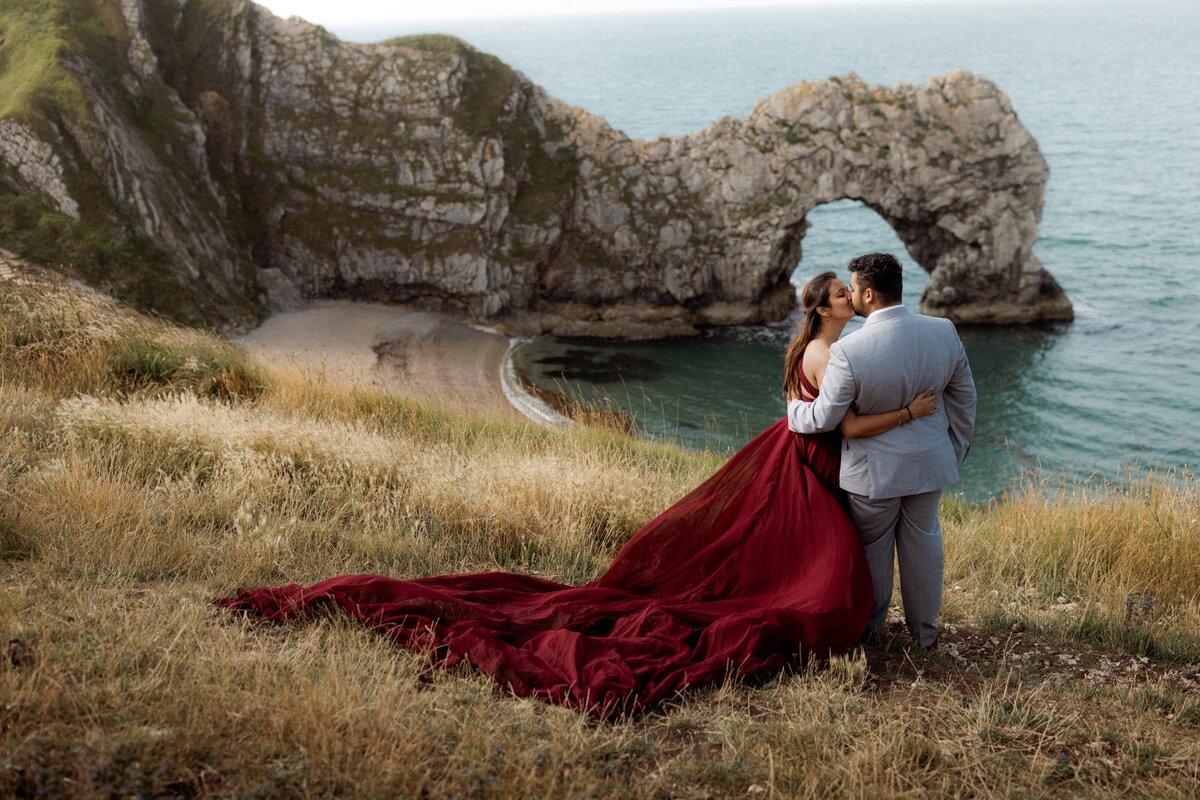 Beach elopement photography couple sharing a sweet kiss posing for UK elopement photographer at Durdle Door in dorset