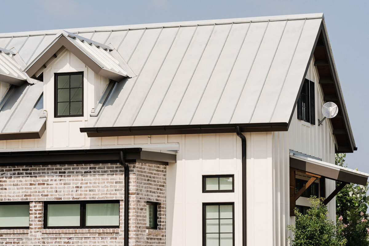 gable standing seam roof on white board and batten building with black windows