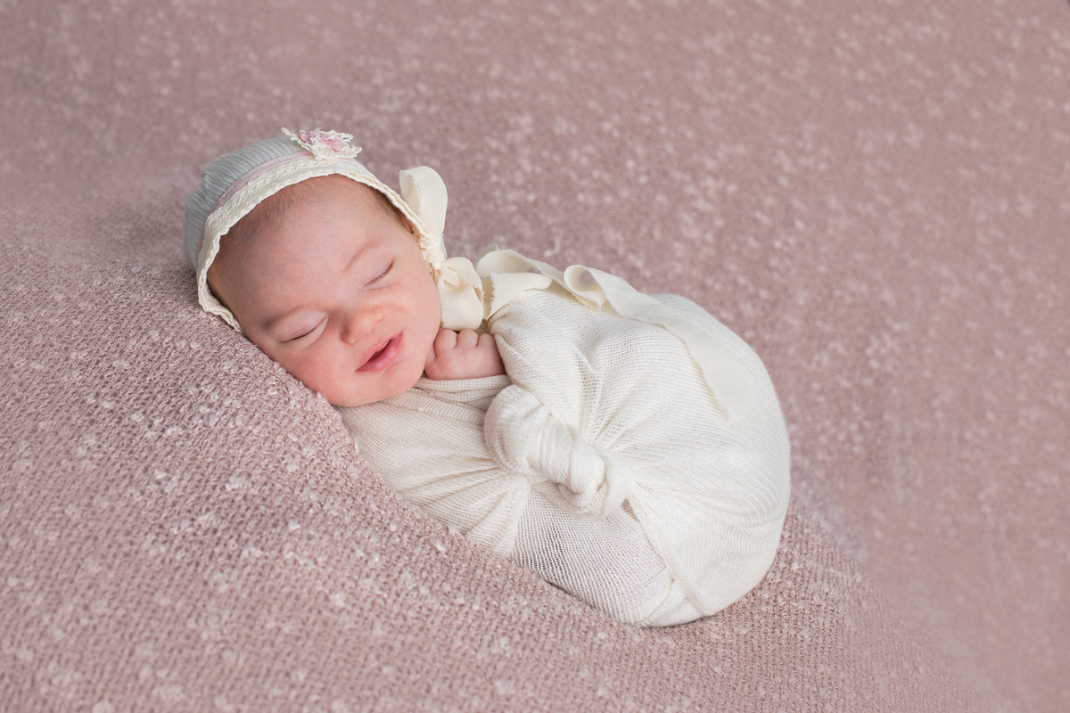sweet little girl in white wrap on pink bed
