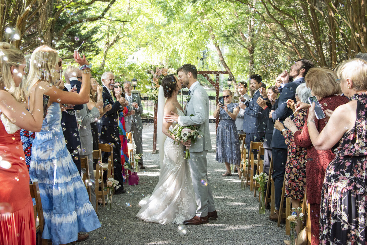 Couple kissing during wedding recessional at Hawkesdene