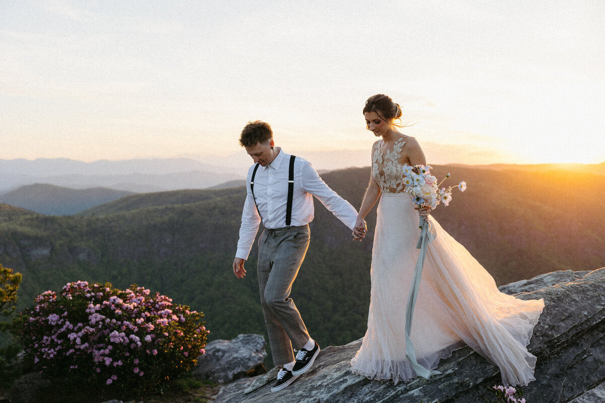 Bride and groom holding hands sunlit on a mountain top in the Blue Ridge Parkway, by Andrea-Marie Photography