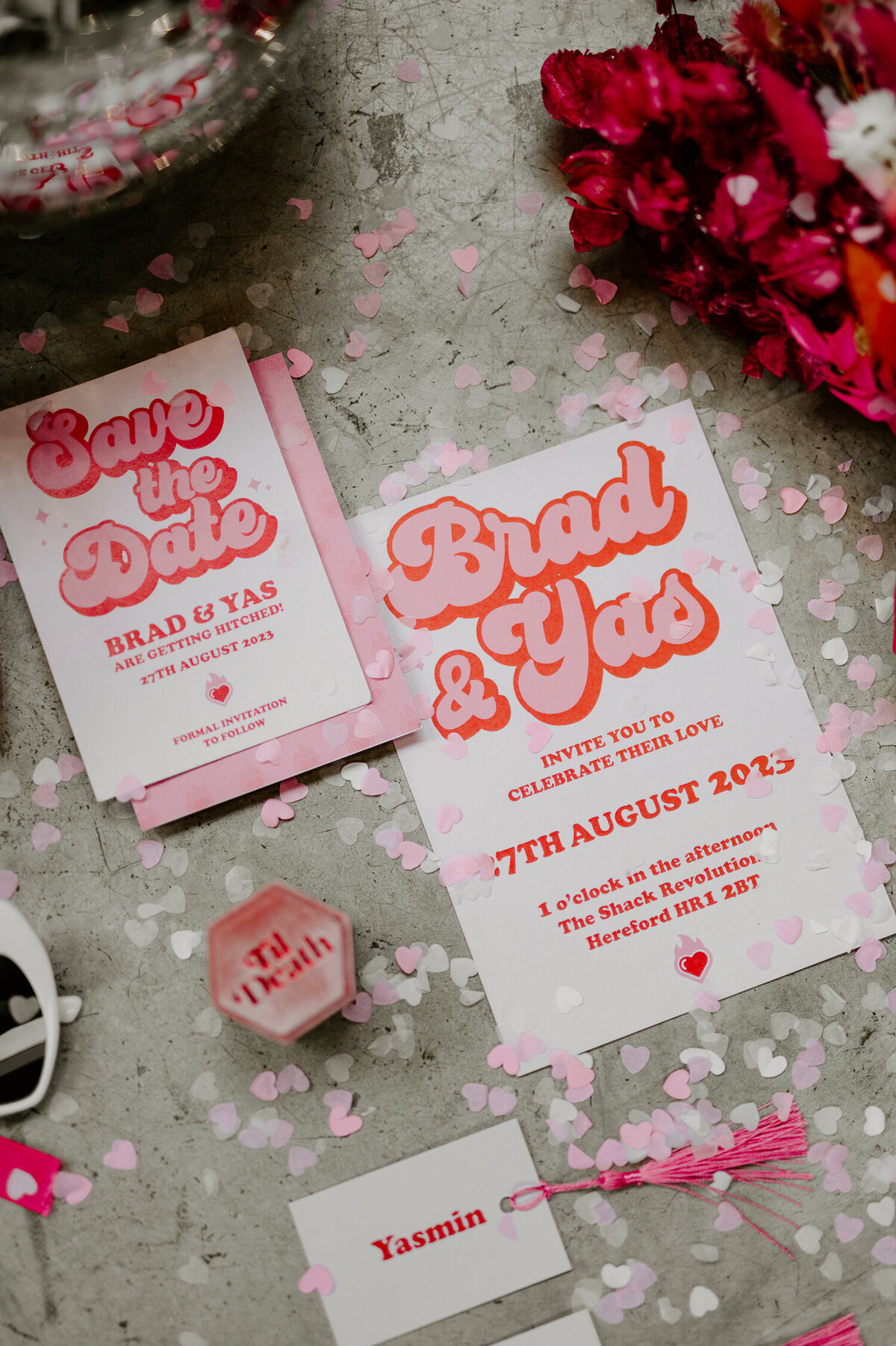 Pink 70s wedding stationery and other details lay on the concrete floor of the shack revolution.