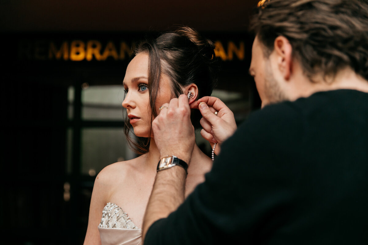 Stylist Tommy Driessen doet een oorbel in bij zangeres Danique Duséé in een gala jurk.