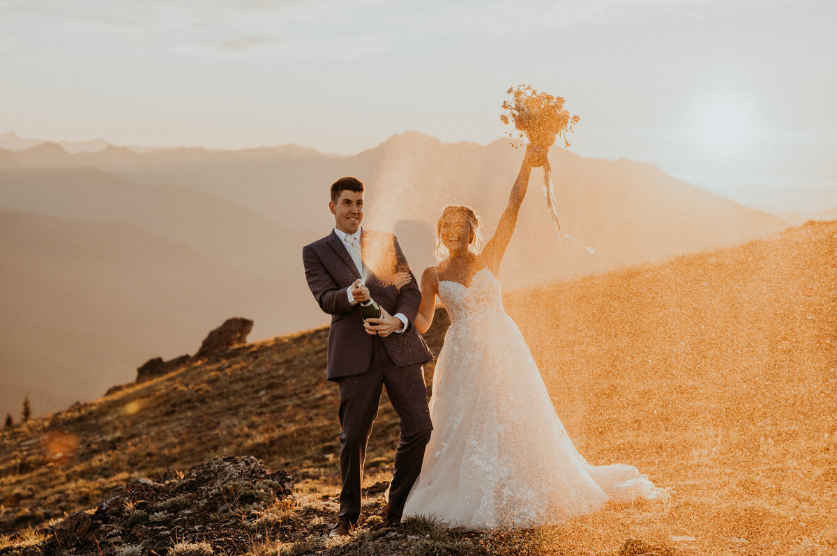Couple popping champagne to celebrate their elopement in the Olympic mountains