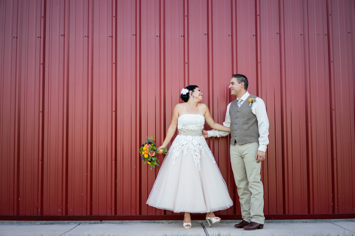 bride and groom in front of red wall at Hye meadow Winery