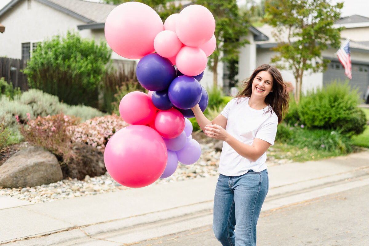 woman holding balloons in the street
