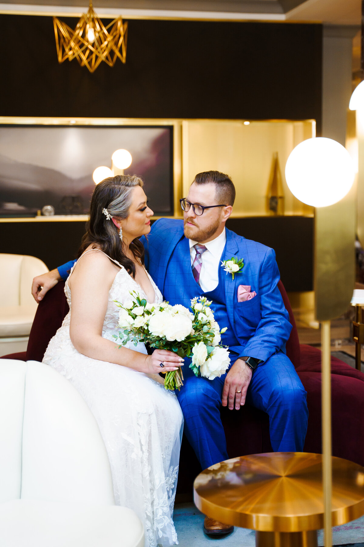 Bride and groom sit on a loveseat and look at each other at a modern hotel - Hotel Leveque in Columbus, Ohio.