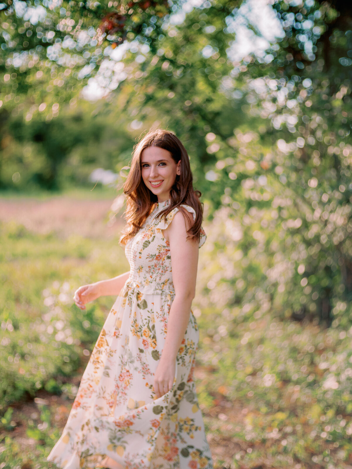 A person twirls in a dress in a forest.