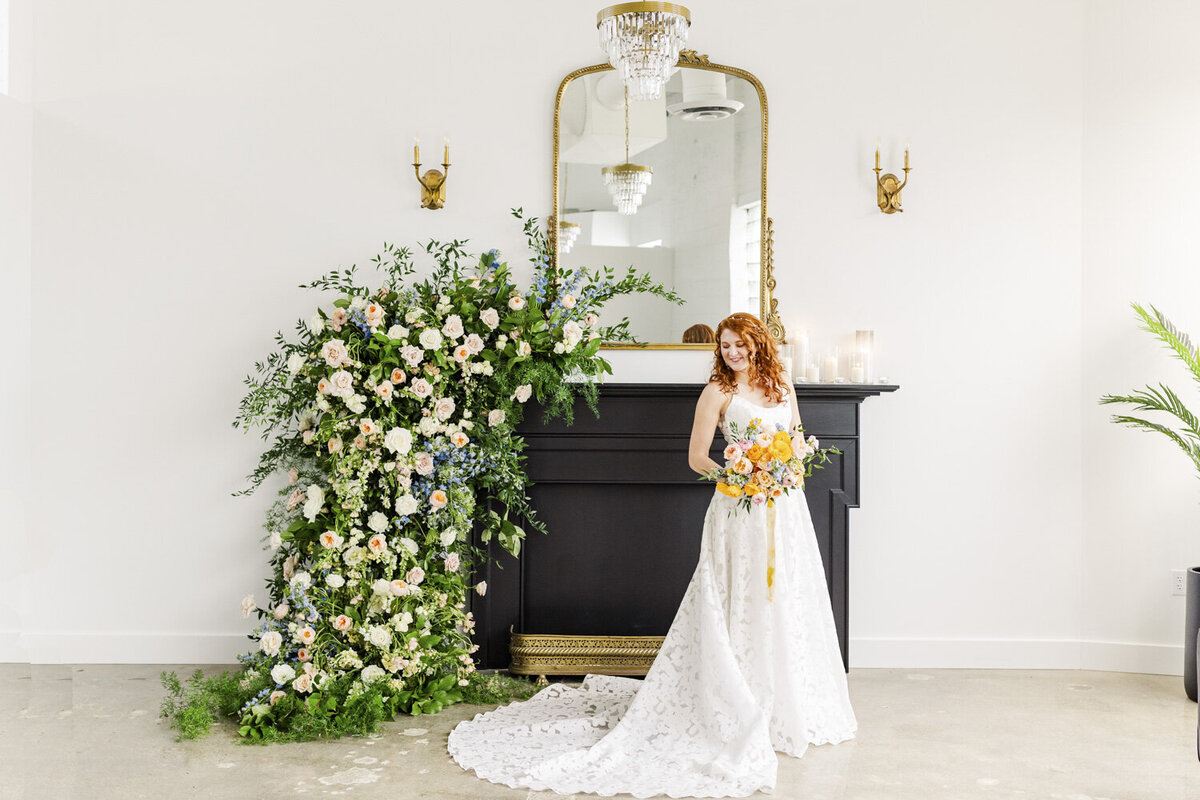 bride standing in front of a fireplace decorated with a flower arrangement