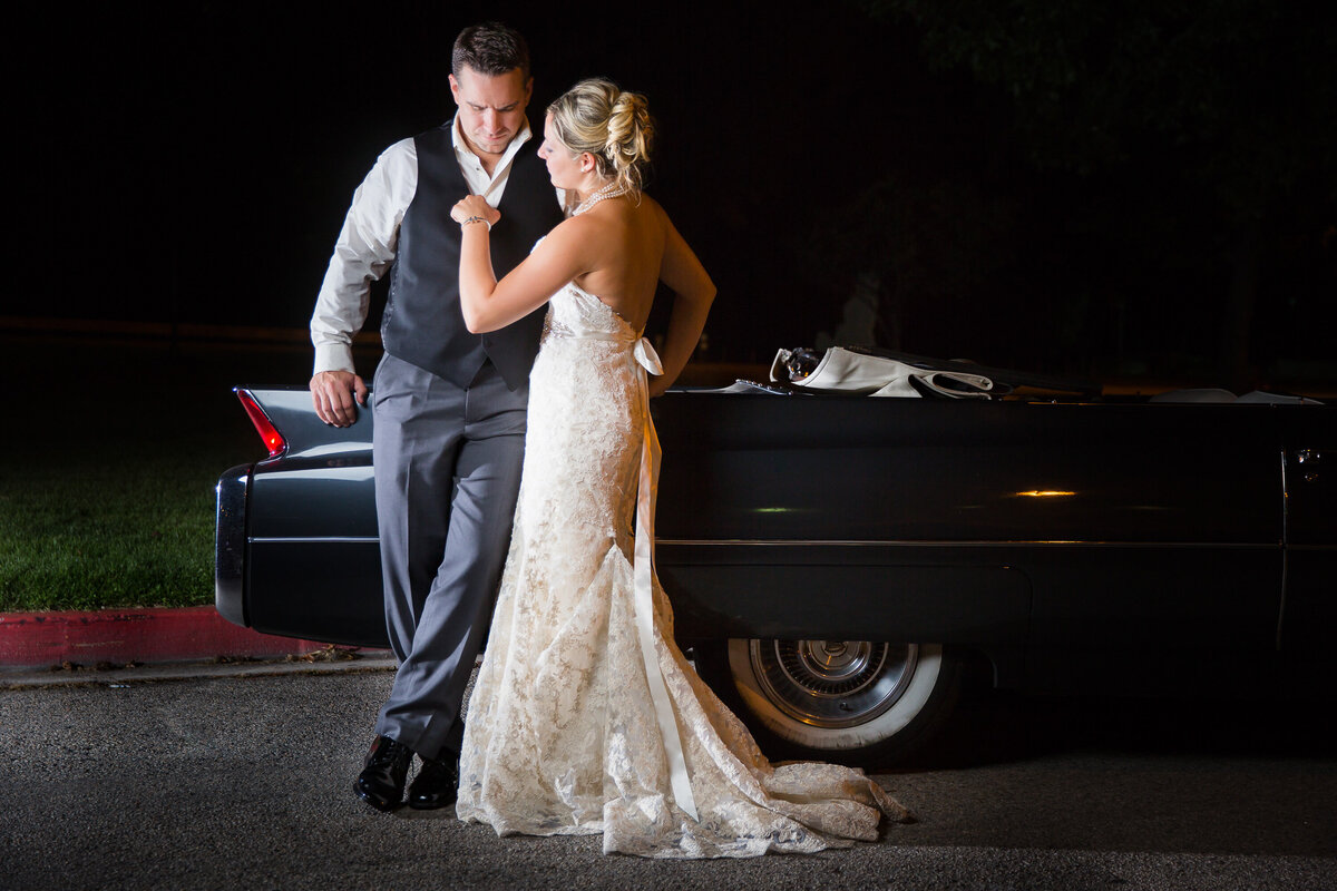 A bride and groom share a moment in front of a classic Cadillac in a break during their wedding reception in Boise, Idaho.