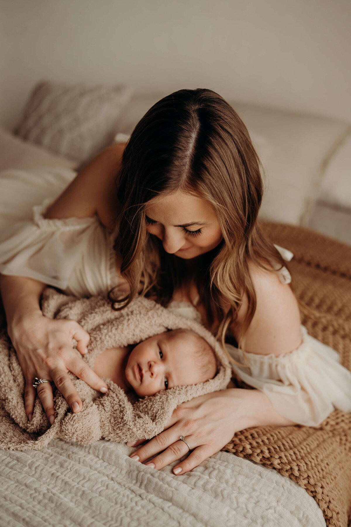 swaddled baby boy looks at camera while swaddled  in a luxury photography studio