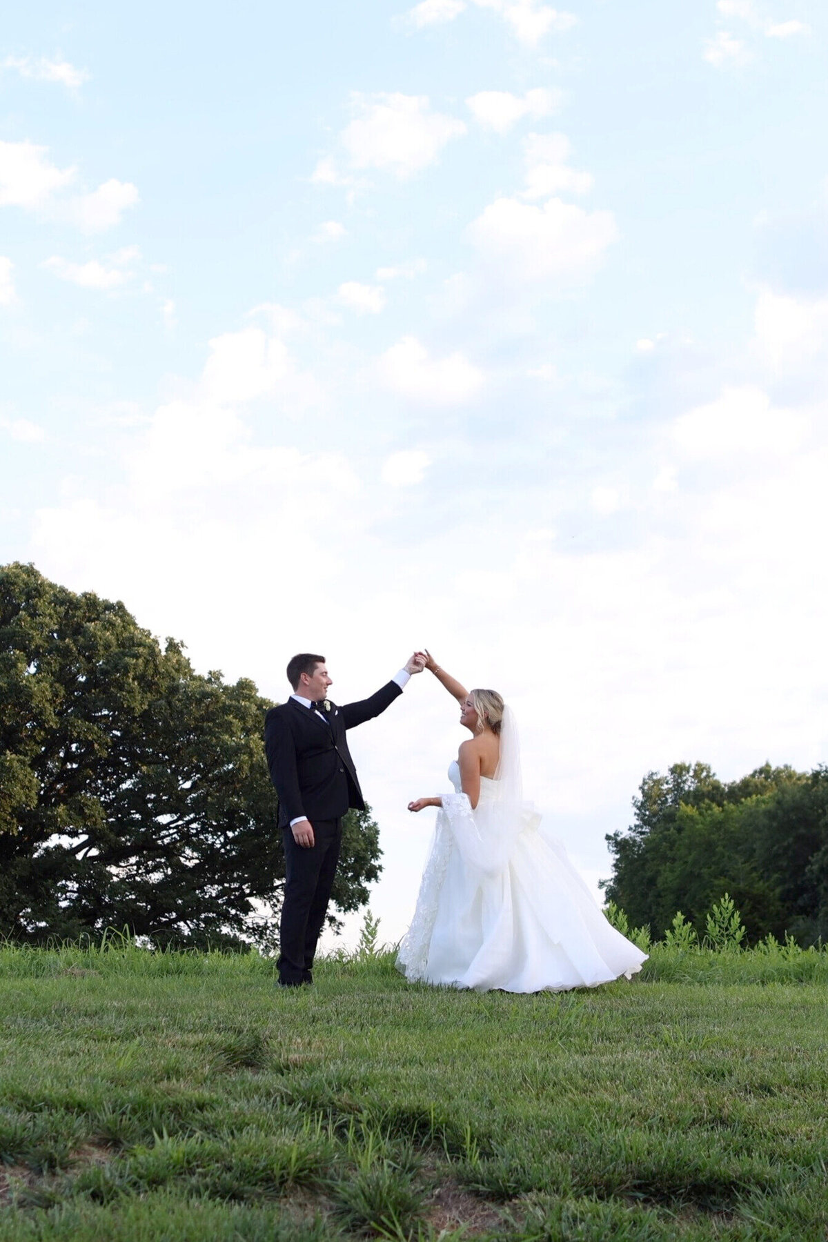 Groom twirling bride on hill at Countryside Chalet