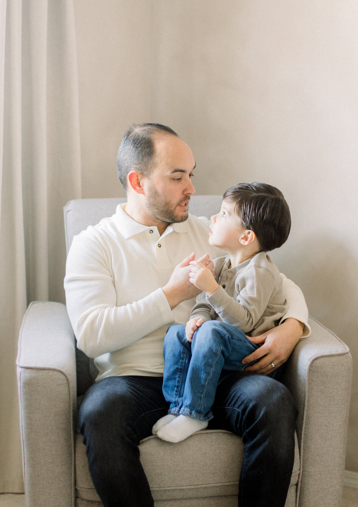 Father and son sitting in a chair together looking into each others eyes