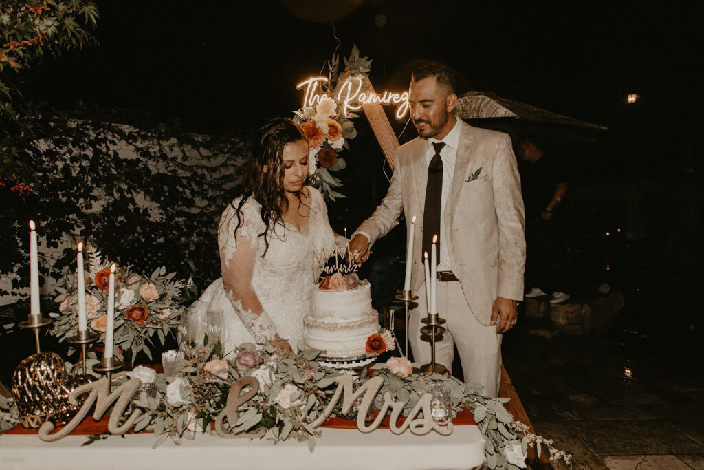 sweet cake cutting moment in front of neon sign of couple's last name