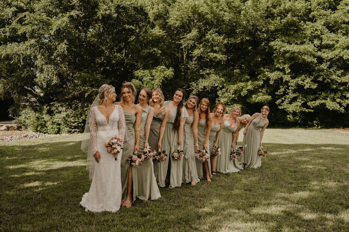 Bride with bridesmaids in sage dresses lined up in a row