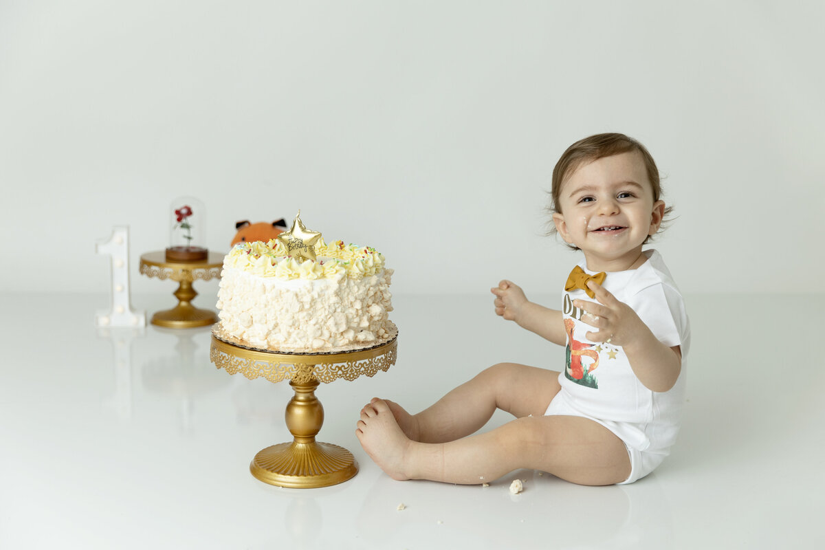 A toddler boy celebrated his first birthday with a yellow cake and gold bowtie in a studio