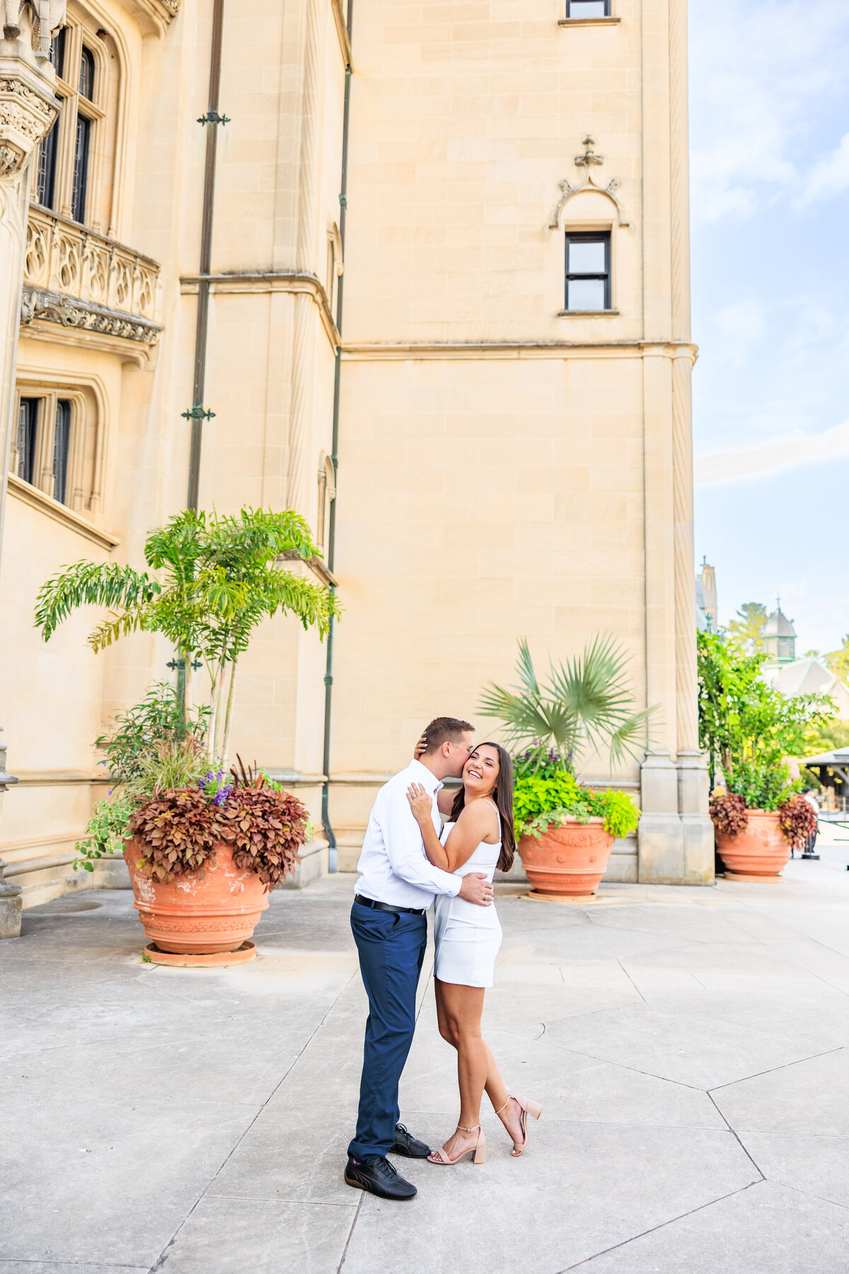 couple with white dress and navy pants holding kiss at Biltmore Estate in Asheville, North Carolina