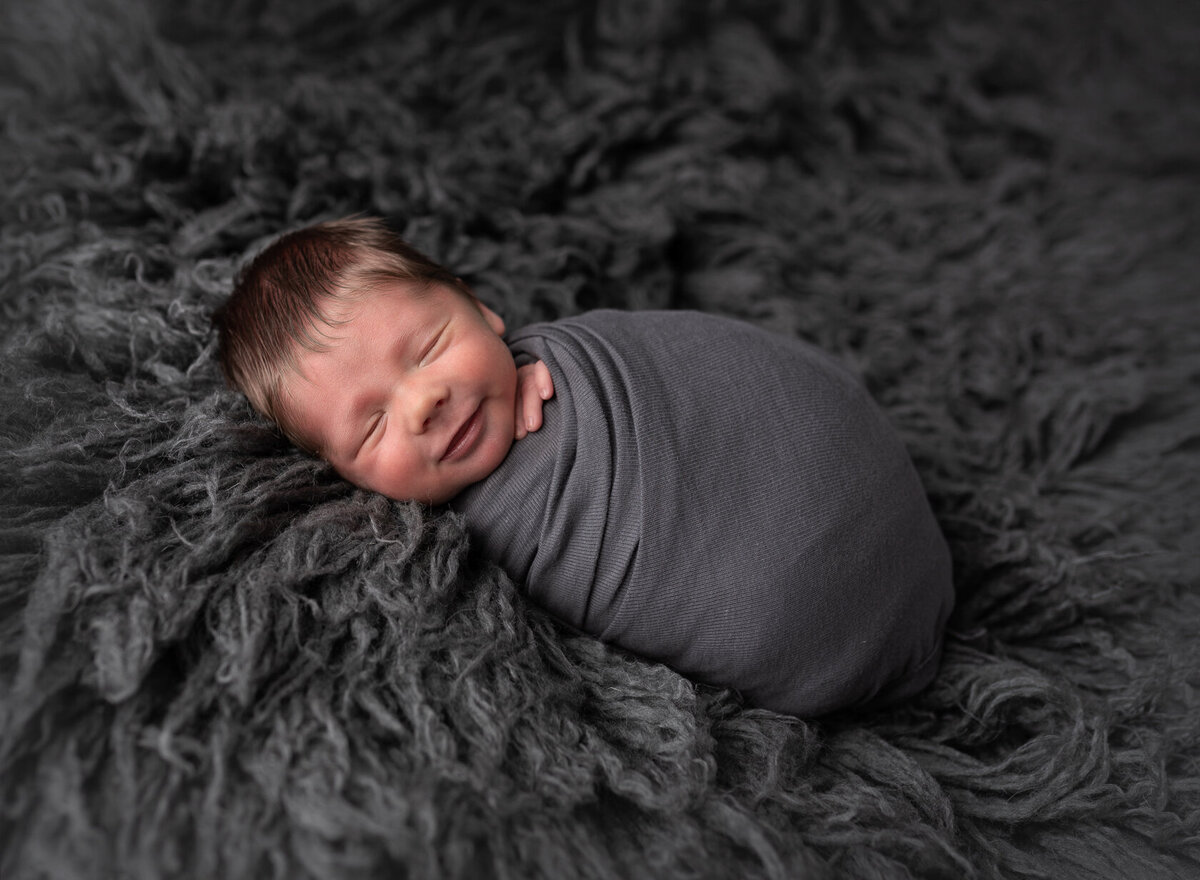 Wrapped smiling newborn in Grey Fur