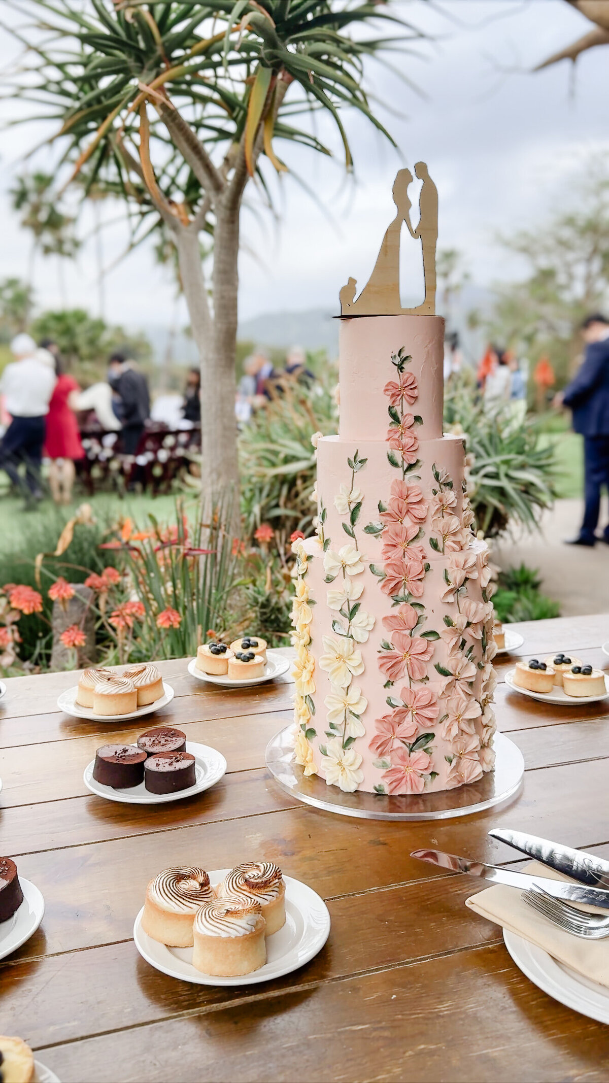 Non-traditional three tiered terracota wedding cake featuring colorful hollyhocks by Lila Cake Shop at a San Diego Zoo Safari Park wedding.