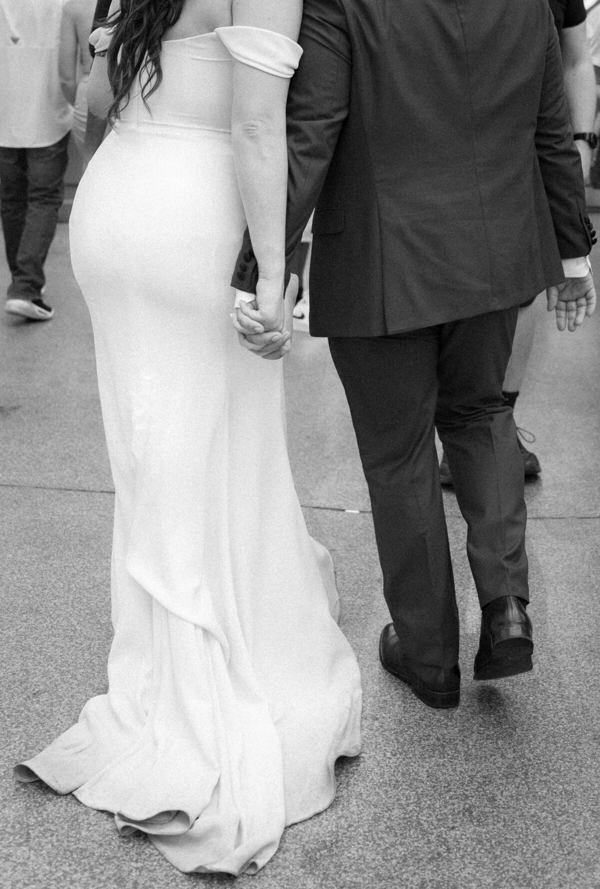Newlyweds holding hands and walking along a sidewalk