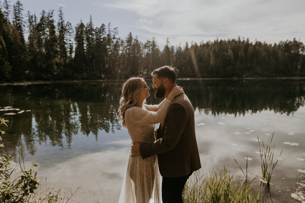 bride and groom holding each other and smiling in front of a lake in Montana