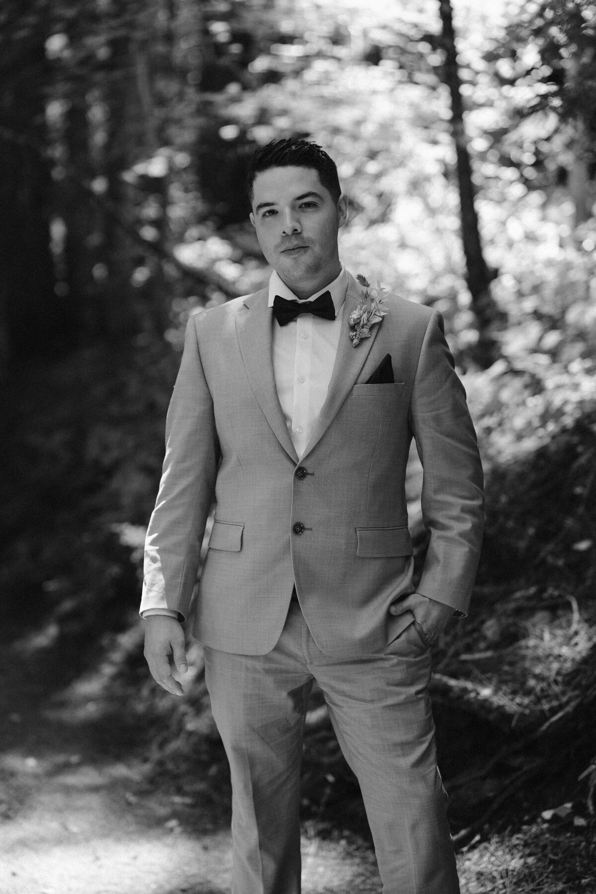 Black and white image of a groom in a tan suit