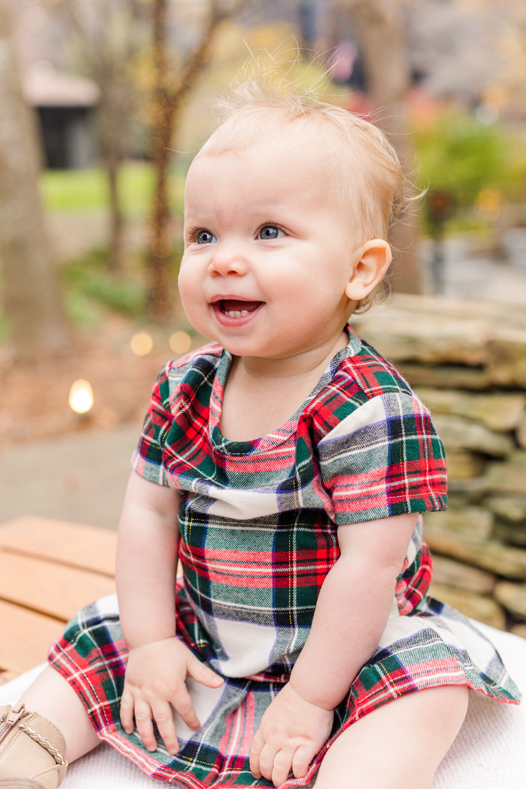 Baby girl in tartan dress sitting on a bench in Ravinia Dunwoody GA