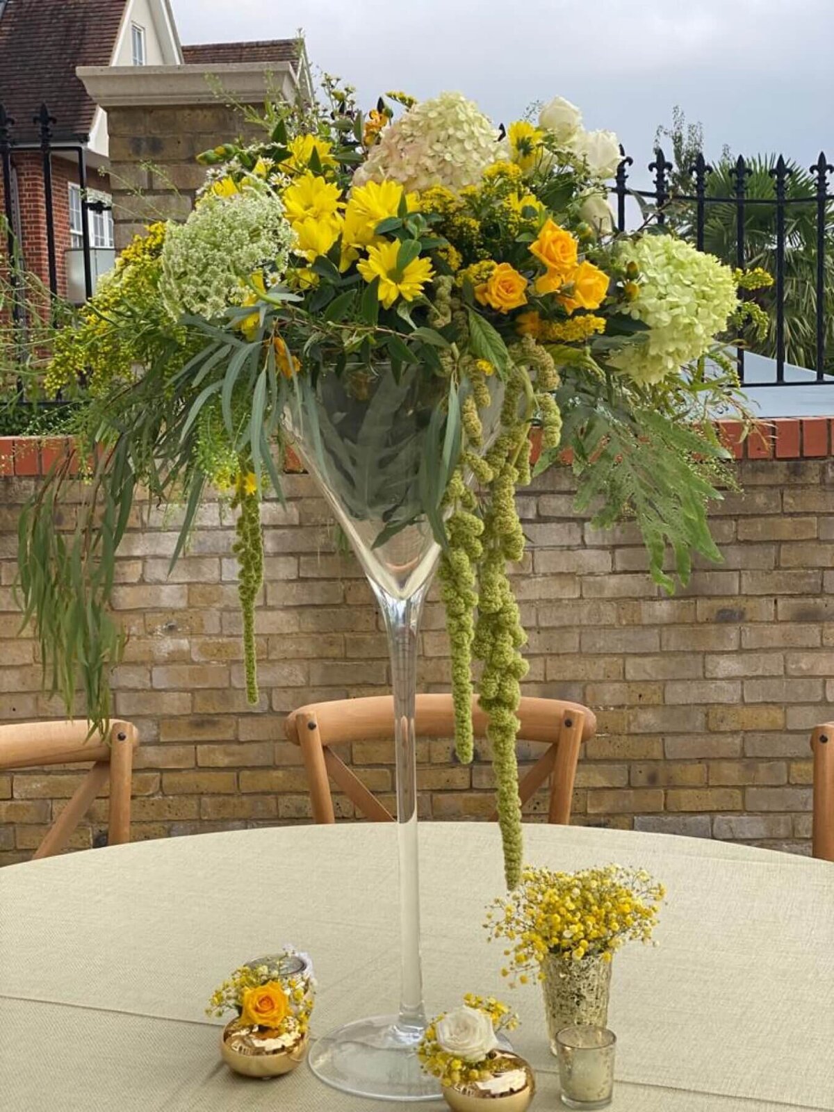 Yellow Flower centrepiece in a large glass vase with small flowers at the bottom