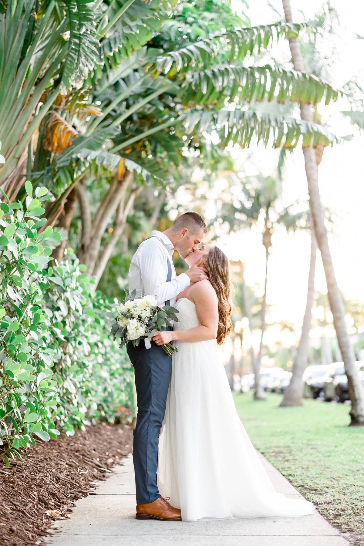 bride and groom on a path with palm trees taken by wedding photographers florida