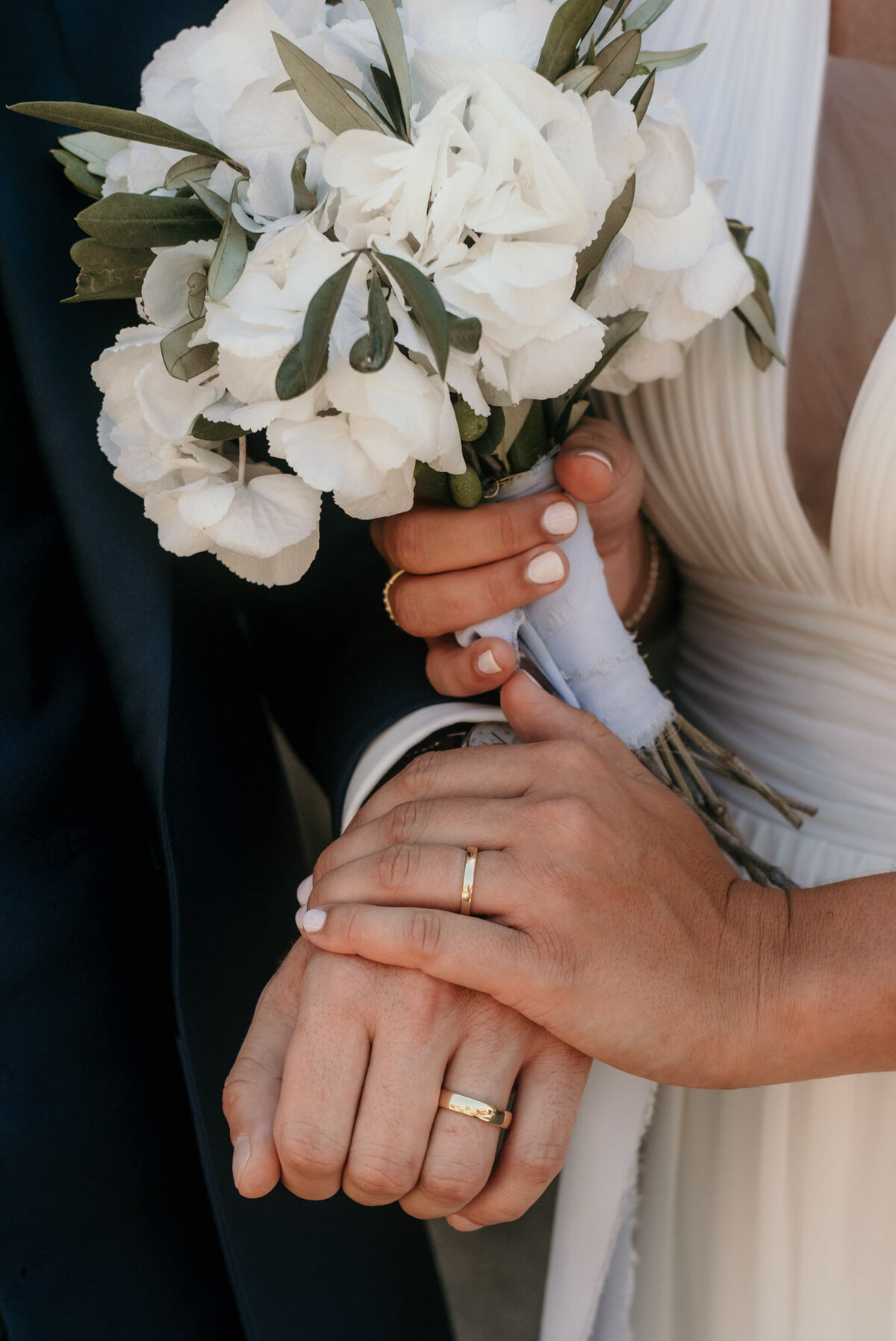 Das Hochzeitspaar legt die Hände mit den Eheringen übereinander in die Kamera.