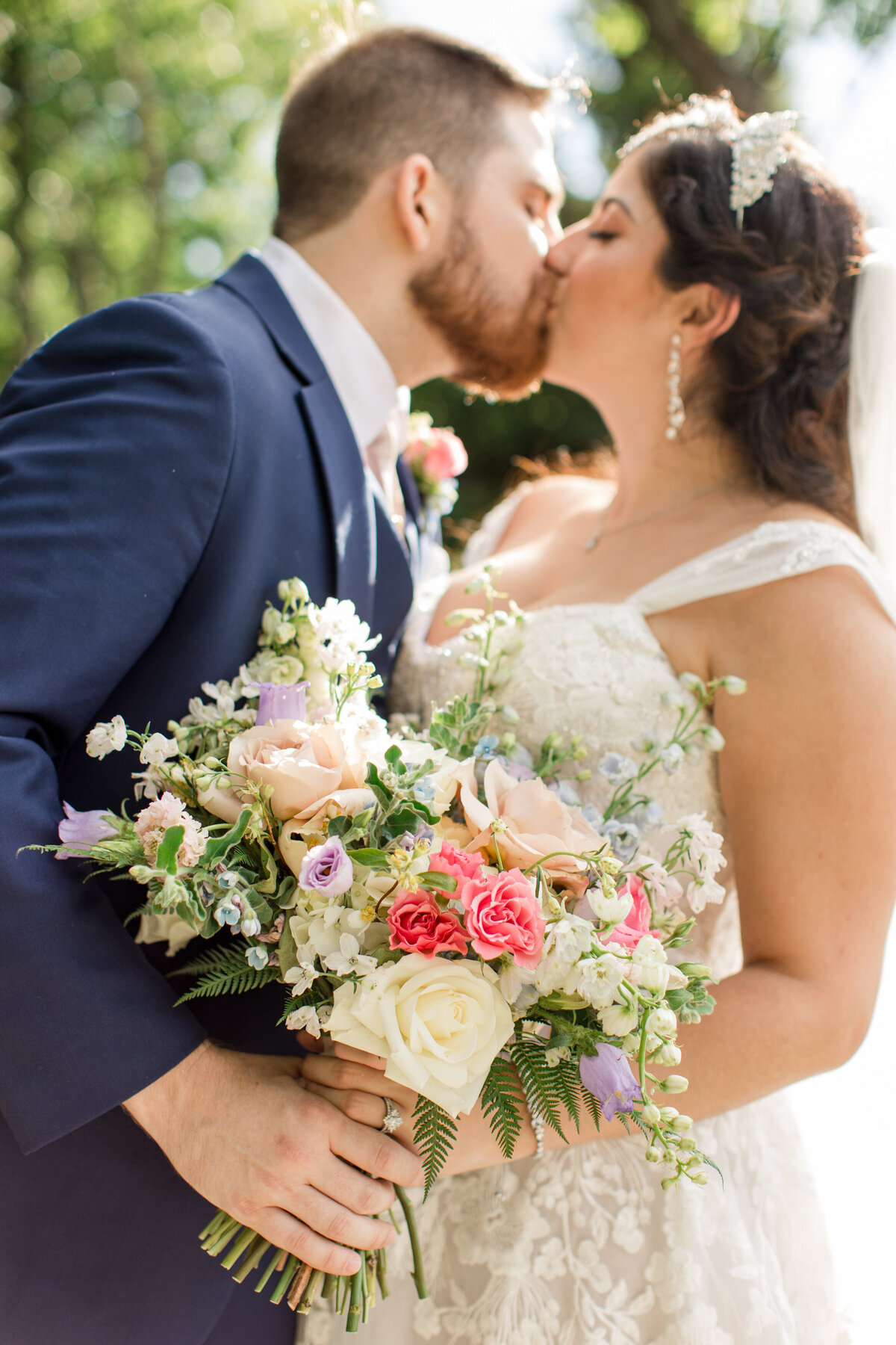 Bride & groom kiss while holding a bridal bouquet for a portrait on their wedding day in West Jefferson, NC
