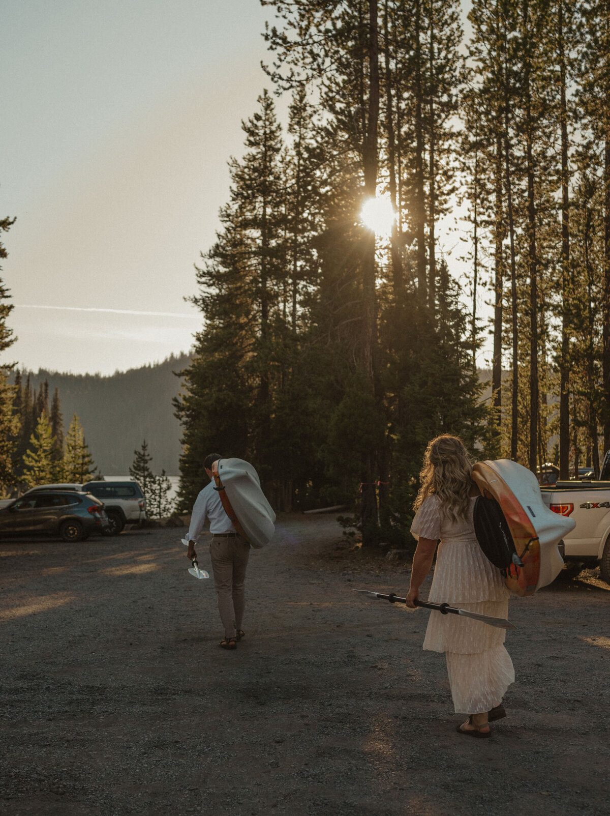 bride and groom carry their kayaks to the lake at sunset in Bend, OR