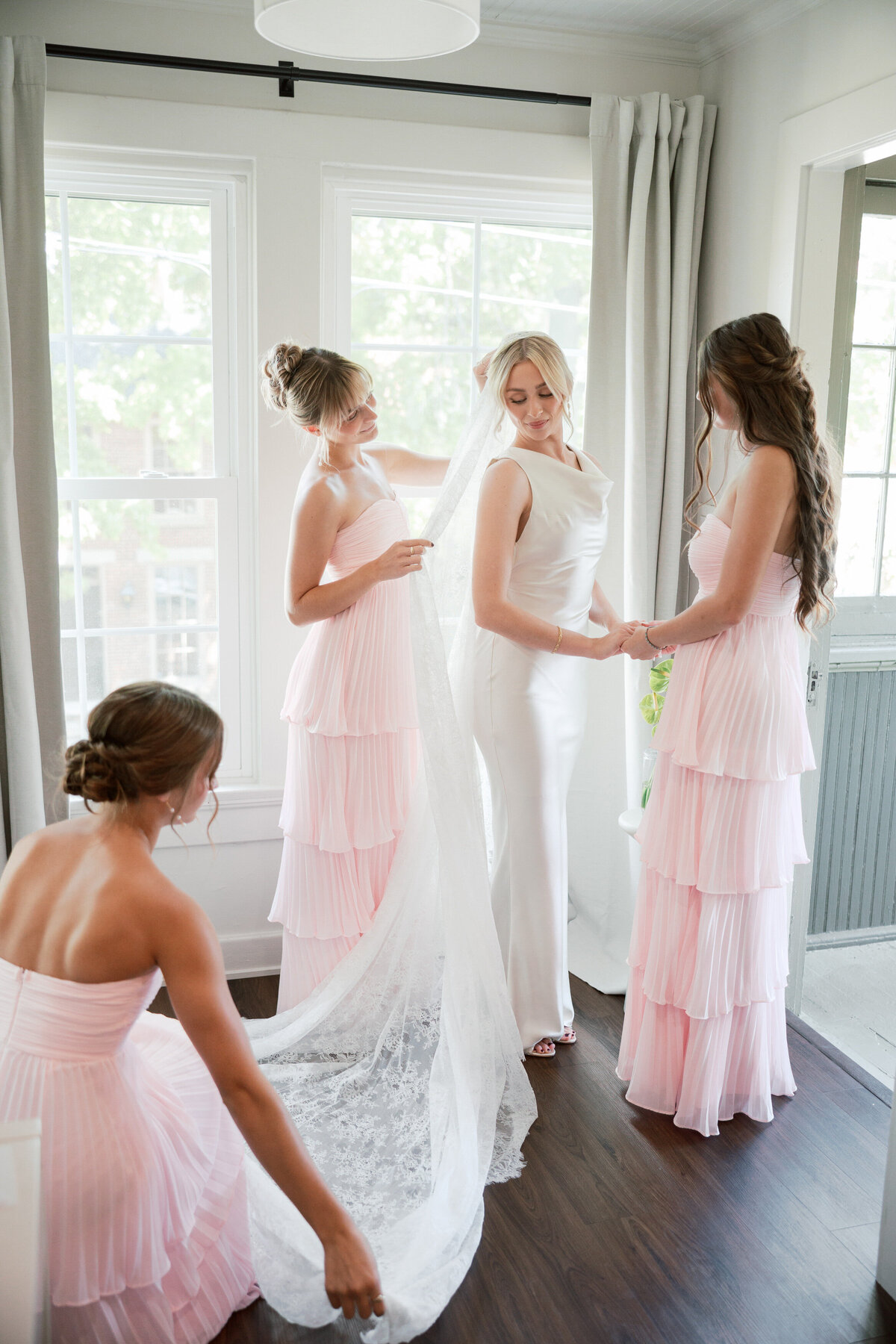 Bridesmaids help bride with lace veil before Dayton ceremony, documented by Philadelphia wedding photographer.