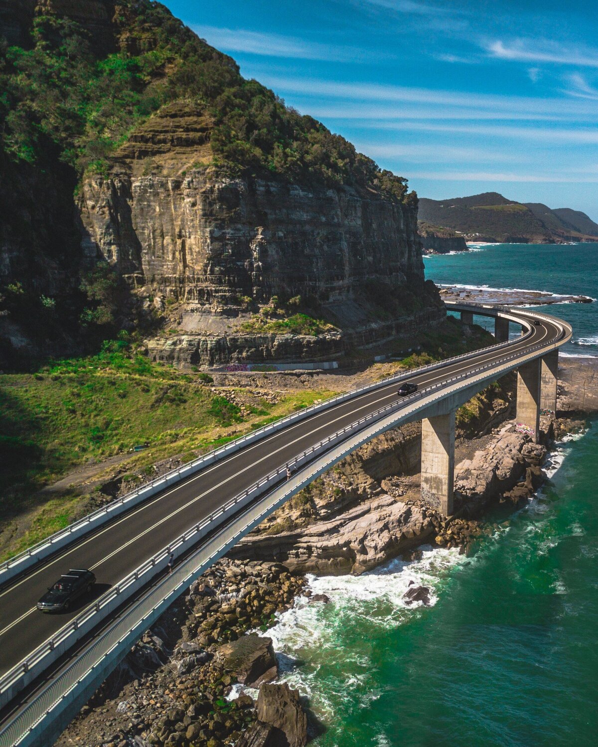 A breathtaking coastal highway winding along the cliffs, overlooking the Pacific Ocean, offering one of the most scenic luxury road trip experiences in California