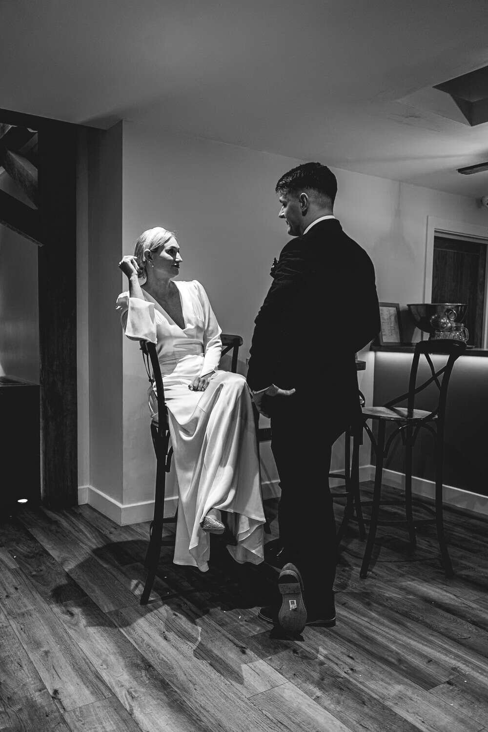 Bride sitting on stool chatting with wedding party