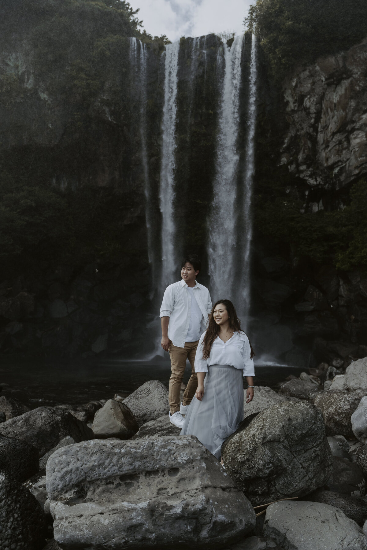 the couple strike a pose at jeongbang waterfall in jeju island