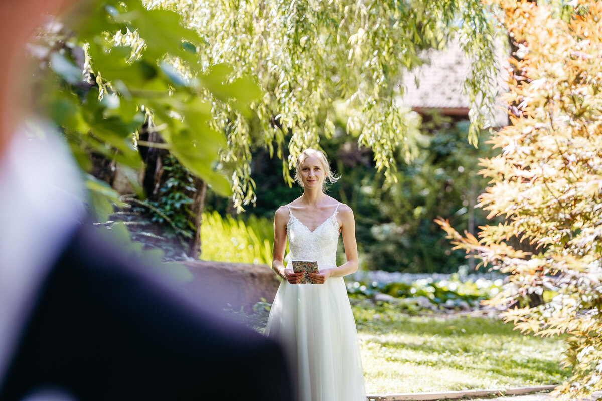 Bride walking toward groom for first look in garden