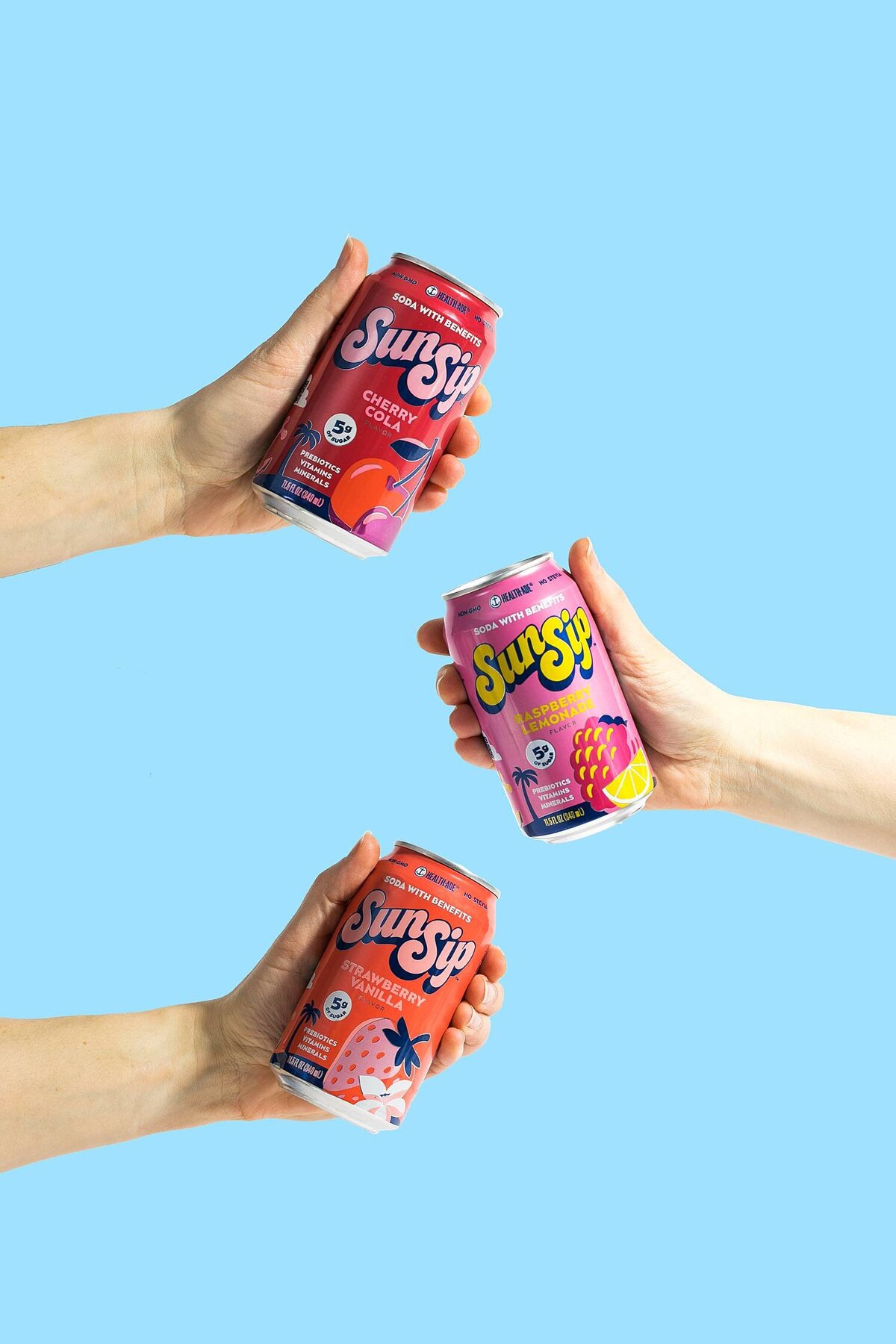 three hands holding colorful cans of sun sip prebiotic soda carbonated drink beverage on a bright blue background