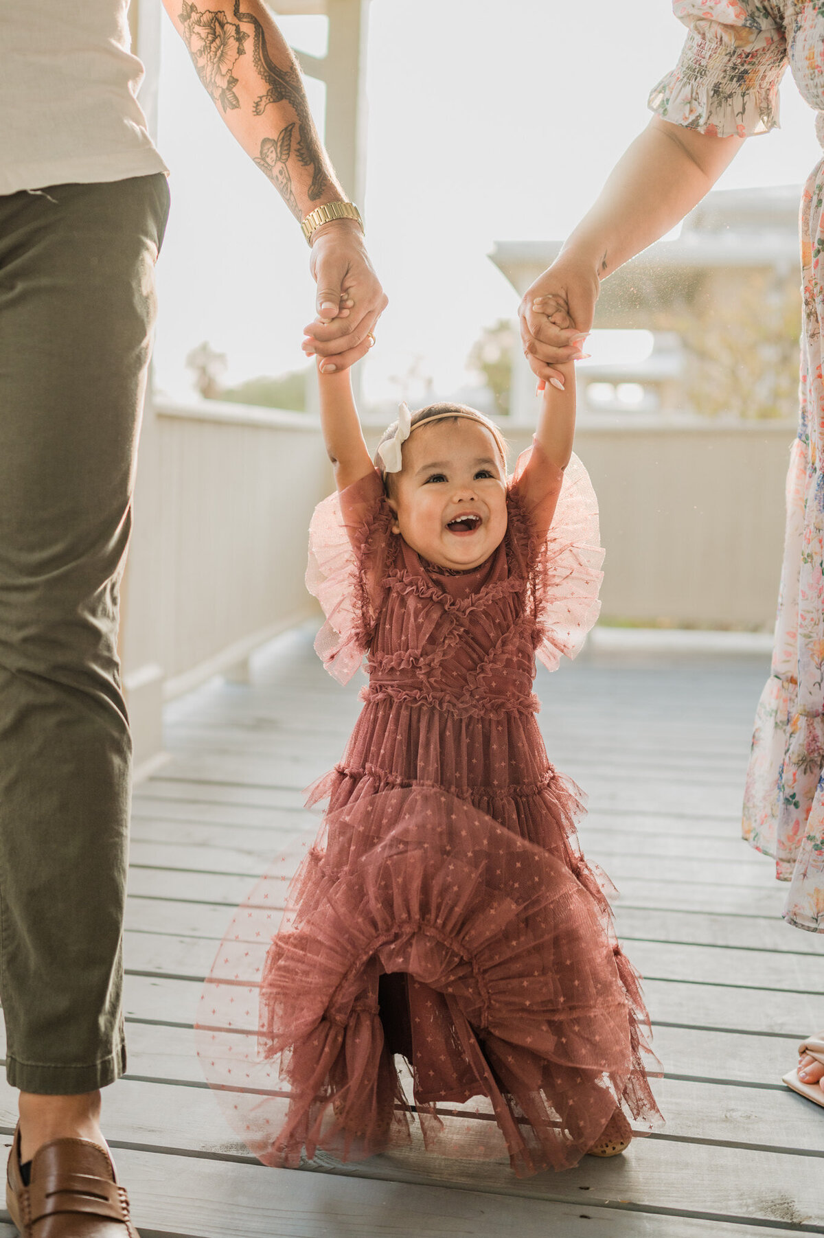 Little girl walks with her parents and laugh during a family photography session.