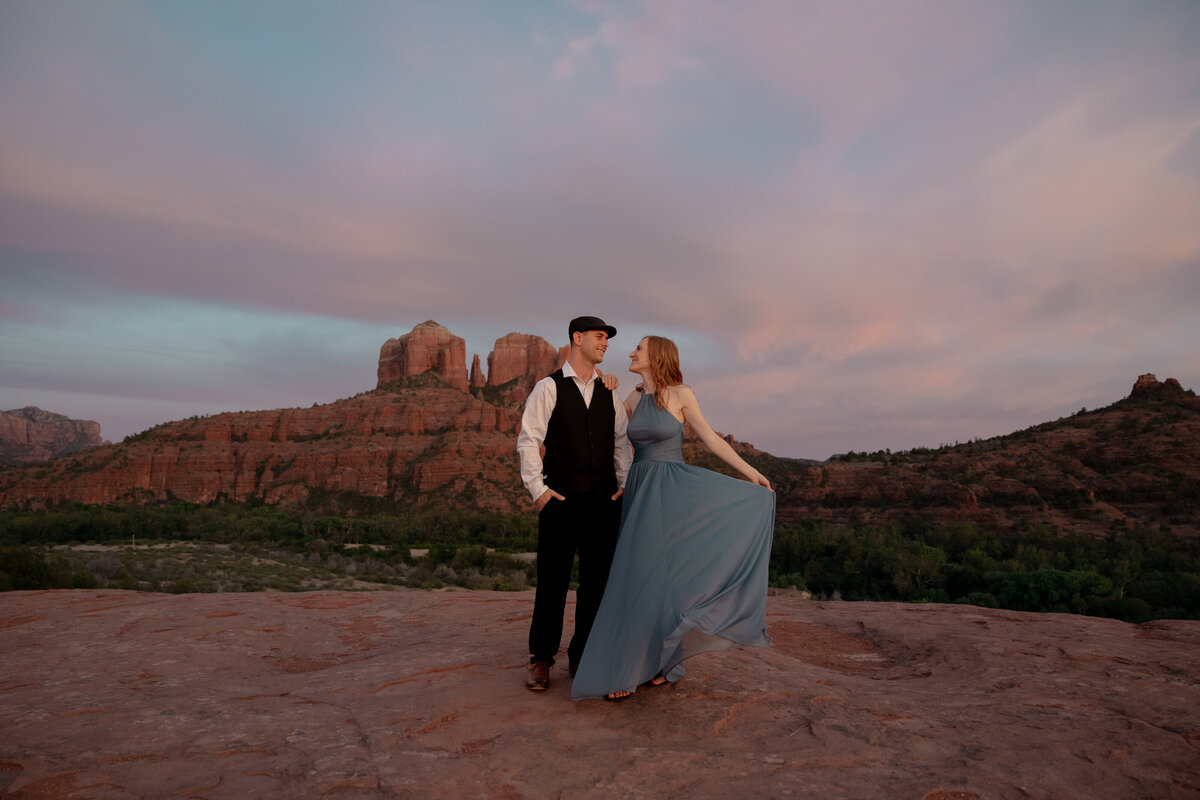 Couple standing against red rock backdrop during Sedona engagement session