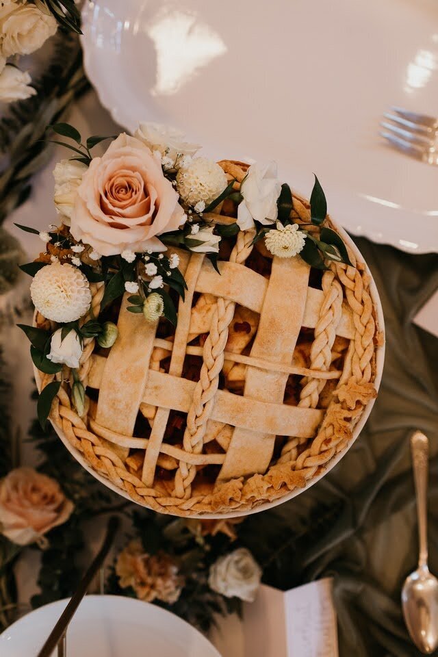 Flowers sit atop a pie at a wedding reception.