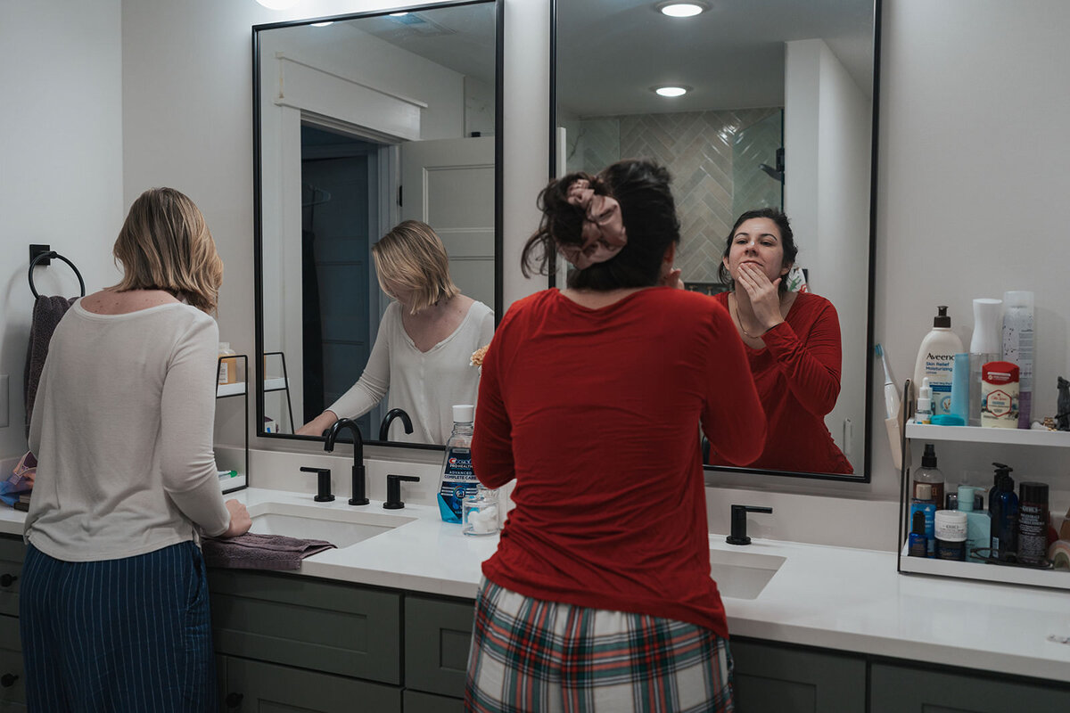 Women remove their makeup in their pj's while looking in the mirror