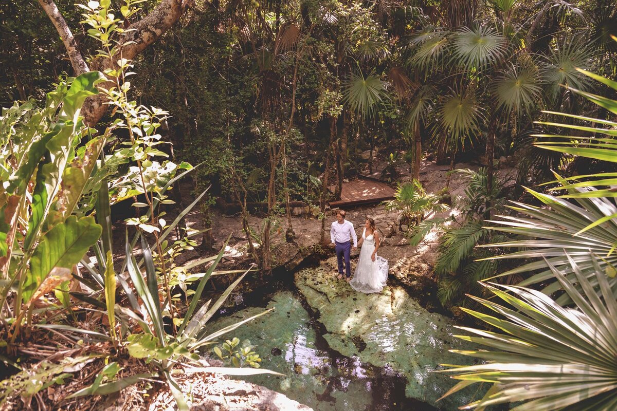 Bride and groom standing near cenote in the jungle in Riviera maya Mexico